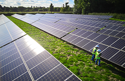 Aerial Drone Shot Of Engineers Inspecting Solar Panels In Field